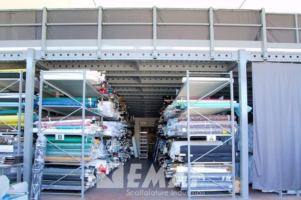 Al piano inferiore di questo soppalco stoffe stoccate su appositi scaffali